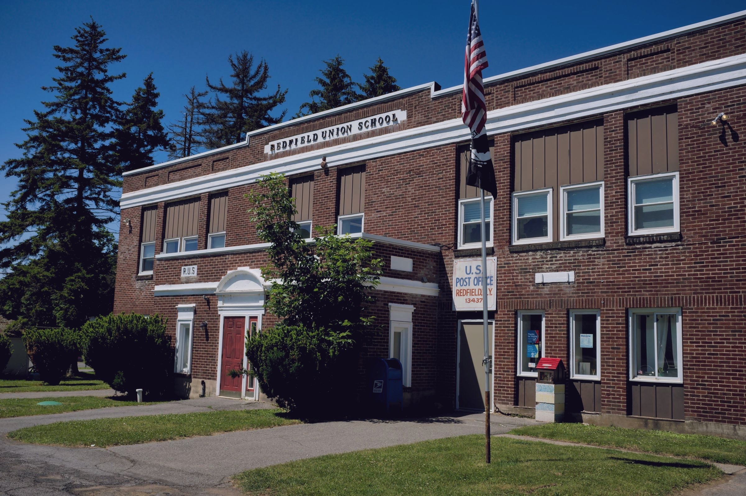 A brick district school building with an American flag out front.